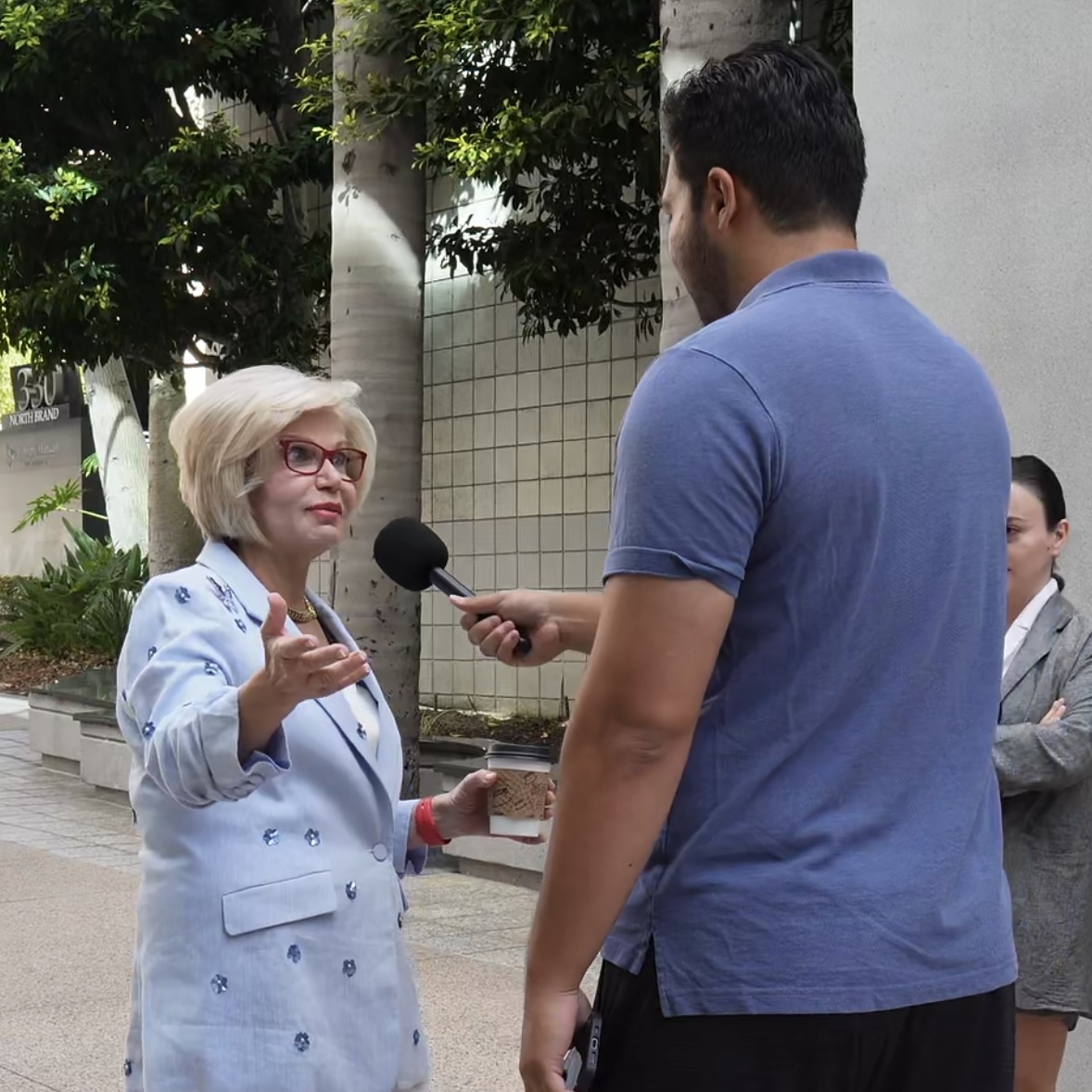 London interviewing a professional woman on the street, mic in hand